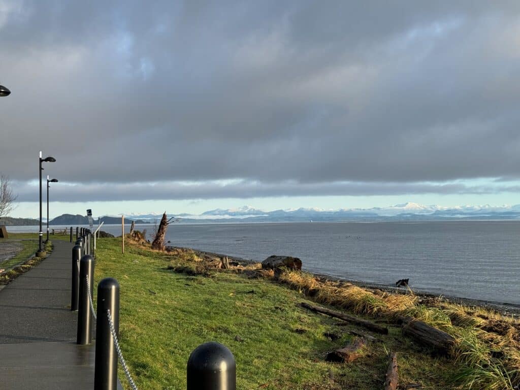 The beachside walking path in Port Hardy, BC with low clouds in the sky and mountains visible in the distance.